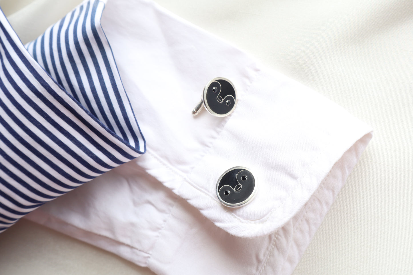 Custom 925 silver cufflinks with matte and glossy enamel and black onyx eyes, designed as a penguin face. A modern jewelry gift in Singapore with refined packaging.