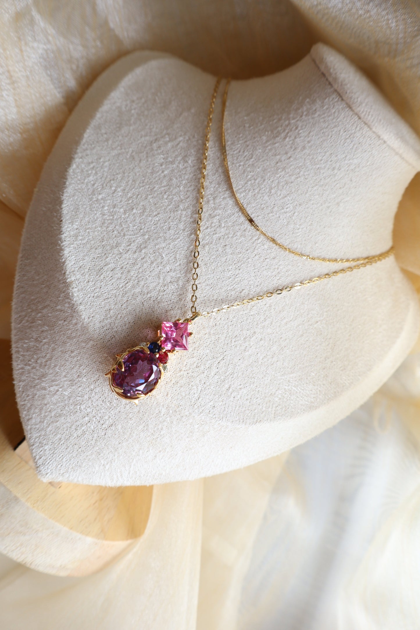 Custom necklace with an oval-cut alexandrite pendant accented by rubellite, ruby, blue sapphire, and natural diamonds on layered chains. Eco-friendly corporate gift jewelry in abaca packaging, bespoke design for Singapore companies.
