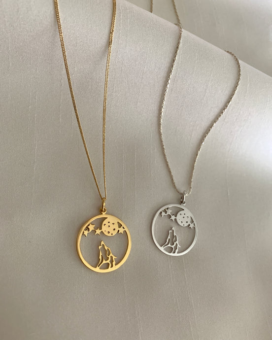 A howling wolf underneath the moon and stars. Set in yellow gold and white gold.