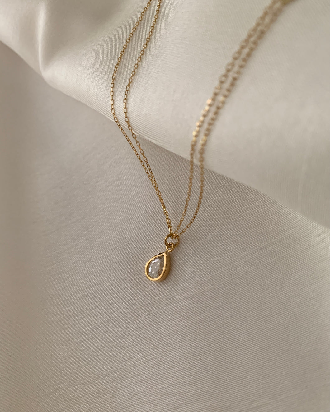 A pear-shaped diamond out into a yellow gold bezel setting necklace.