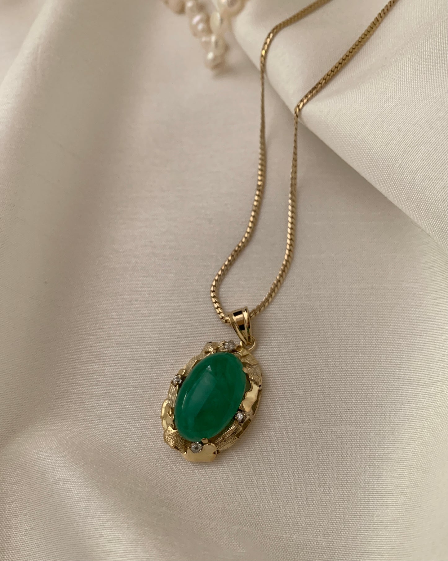 An oval jade stone set in a unique bezzled setting with 5 small round diamonds. All set in yellow gold.