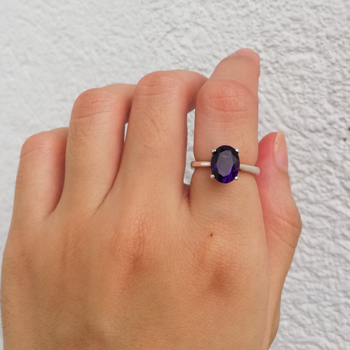 A purple oblong gemstone as the center of the ring. Set in white gold.