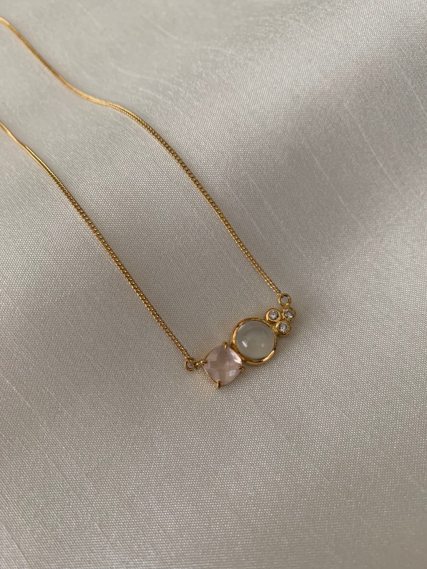 A peach cushion morganite, moonstone at the center and 3 small russian diamonds. Put into a yellow gold necklace.