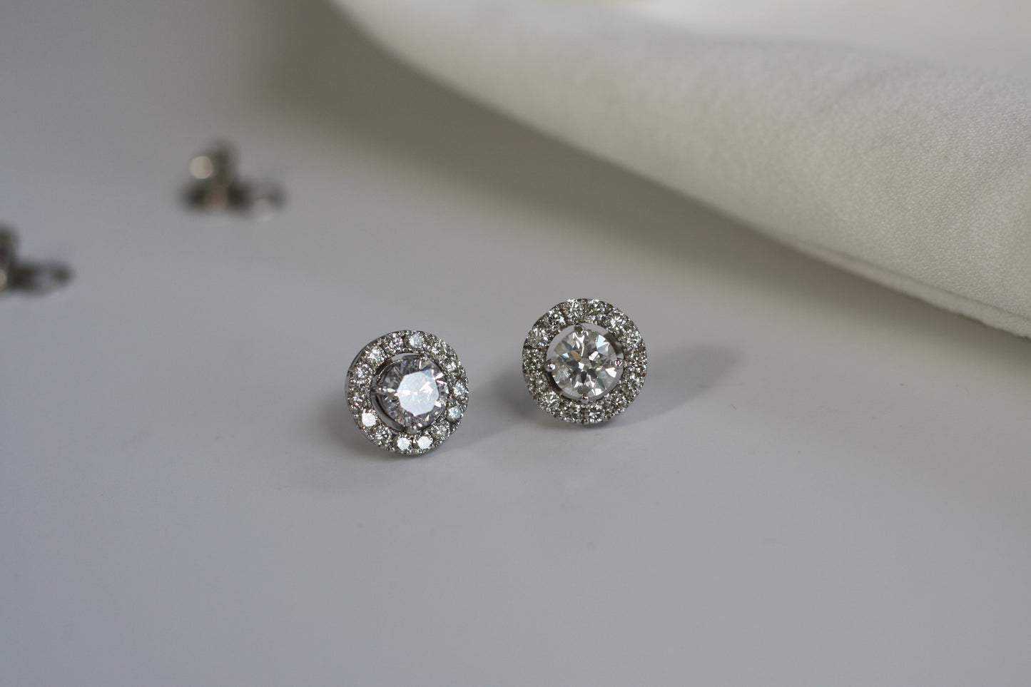 2 round sparkling diamond earrings with halo in white gold setting.