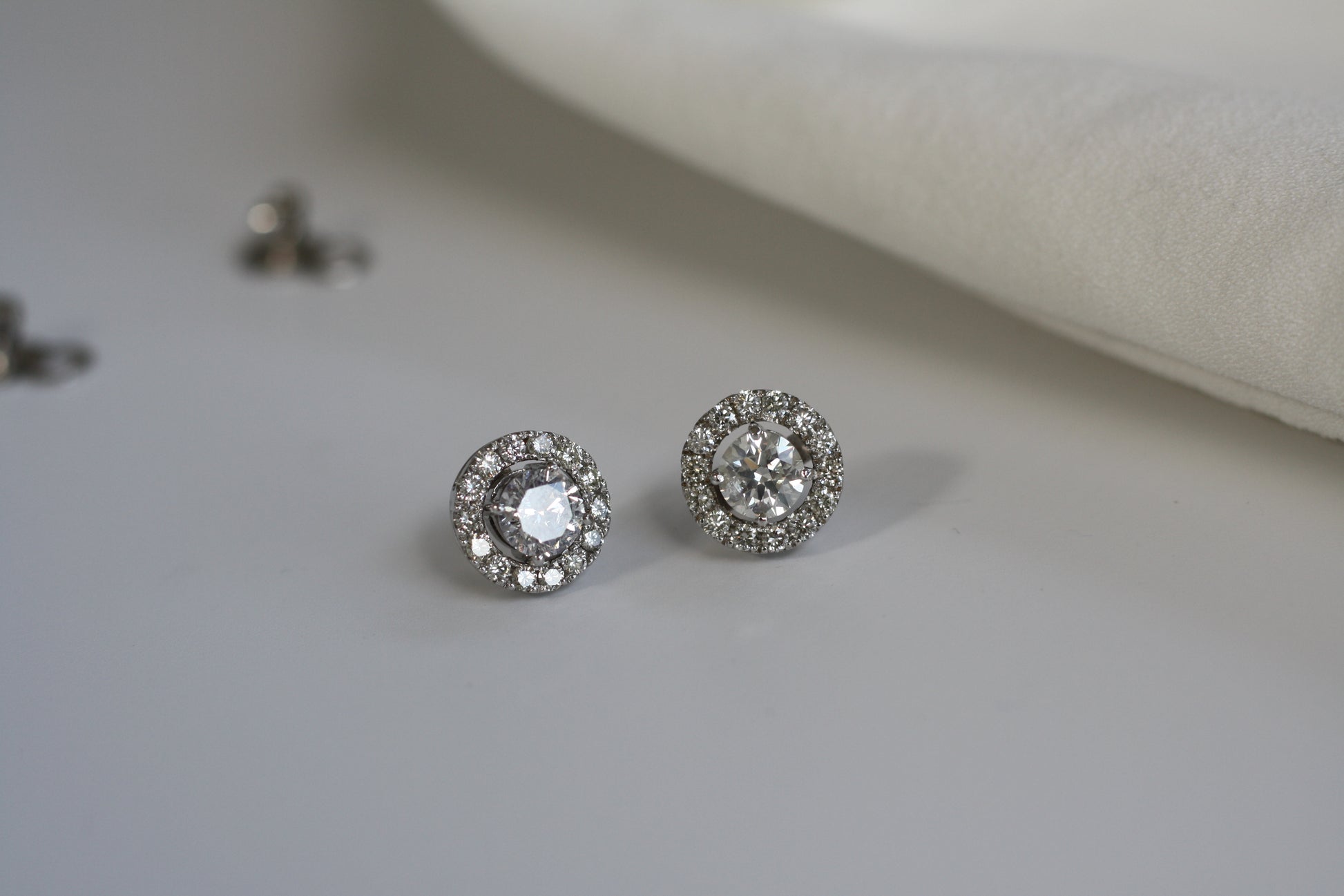 2 round sparkling diamond earrings with halo in white gold setting.