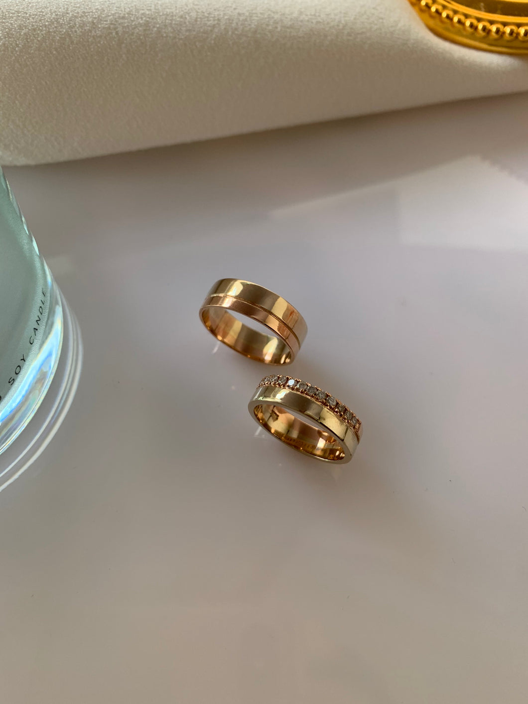 Yellow gold wedding rings. For the bride, the half of the upper ring is surrounded by brilliant small diamonds. For the groom, a classic yellow gold ring brishedd off at the top.