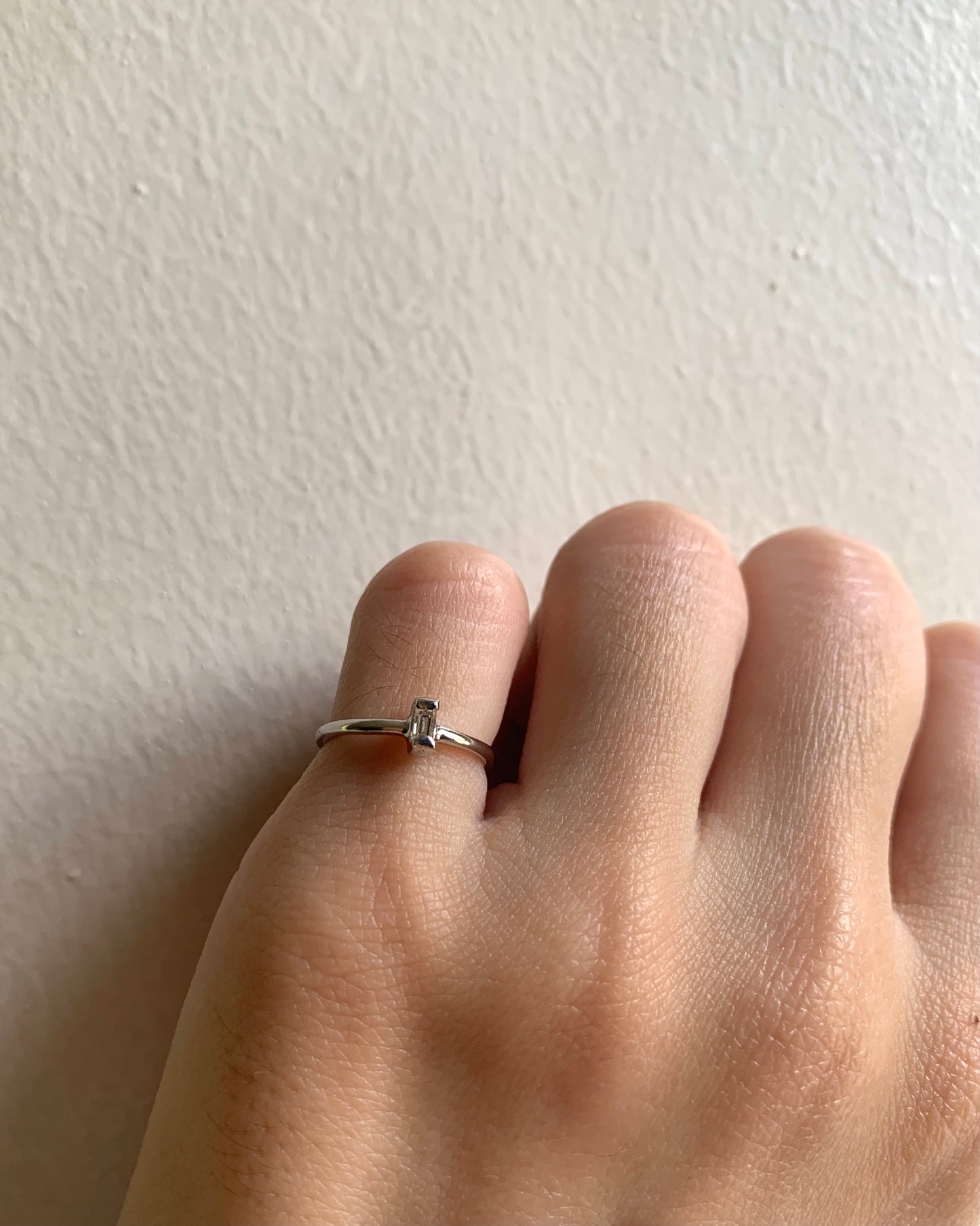 A horizontal rectangular baguette as its center stone set in yellow gold.