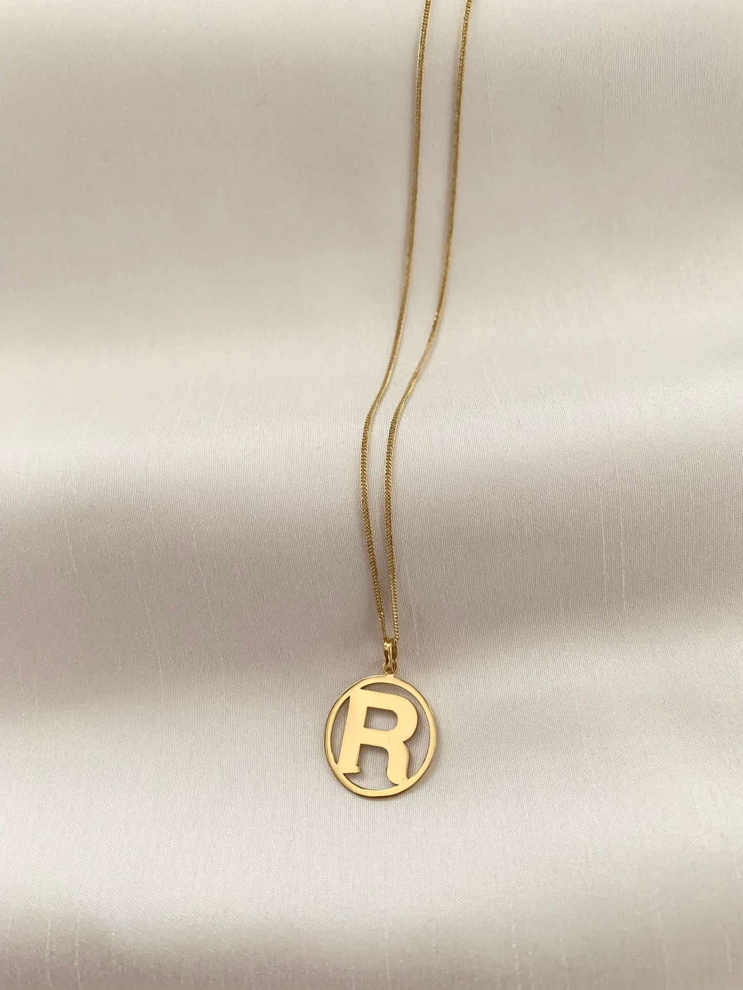 Gold R initial pendant enclosed on an 18k gold too.