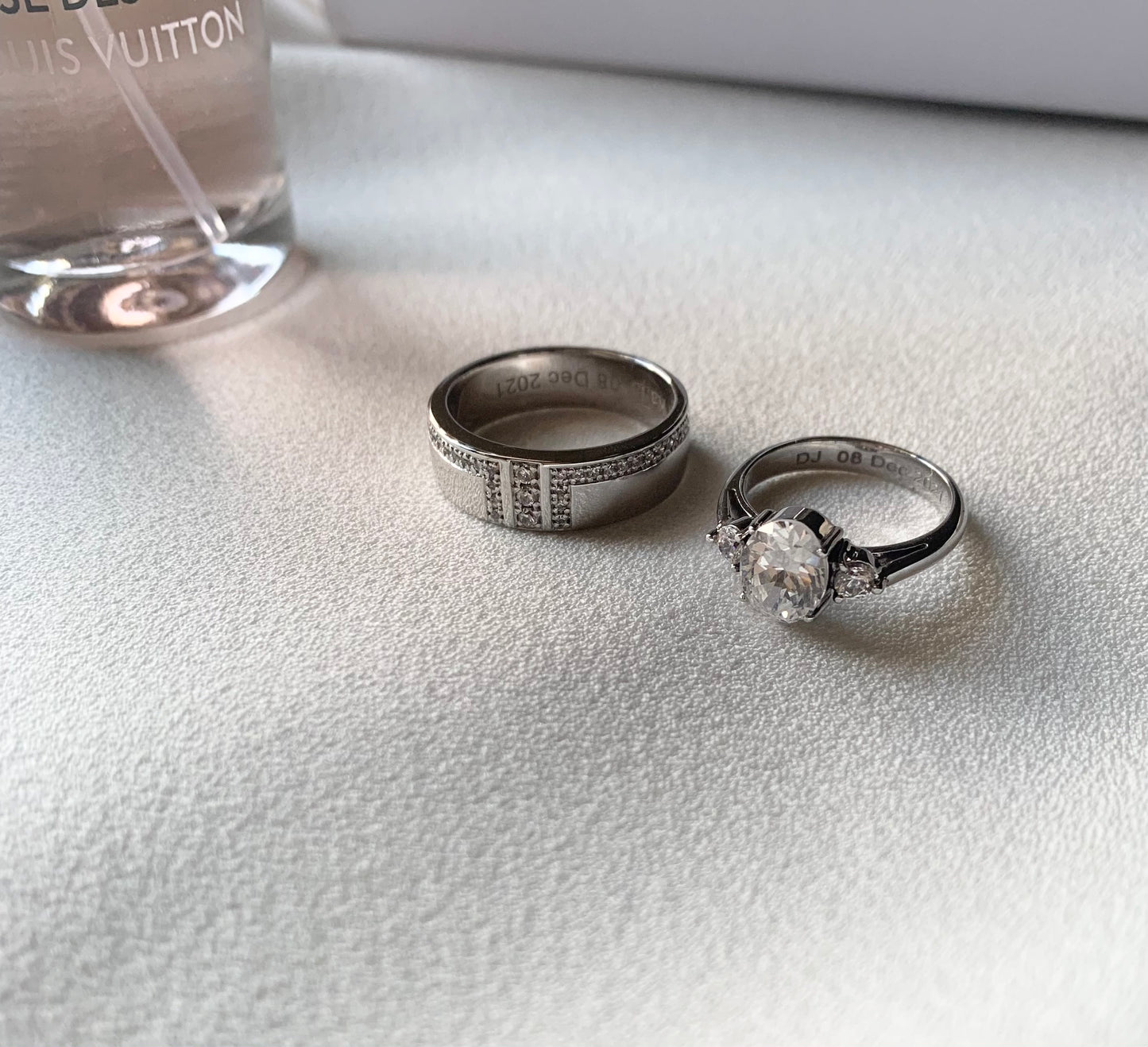 White gold wedding rings. Groom with approximately 30 white sapphires all around the ring itself. Bride: with an oval whute sapphire as the center stone ans 2 small round sapphires at the side.