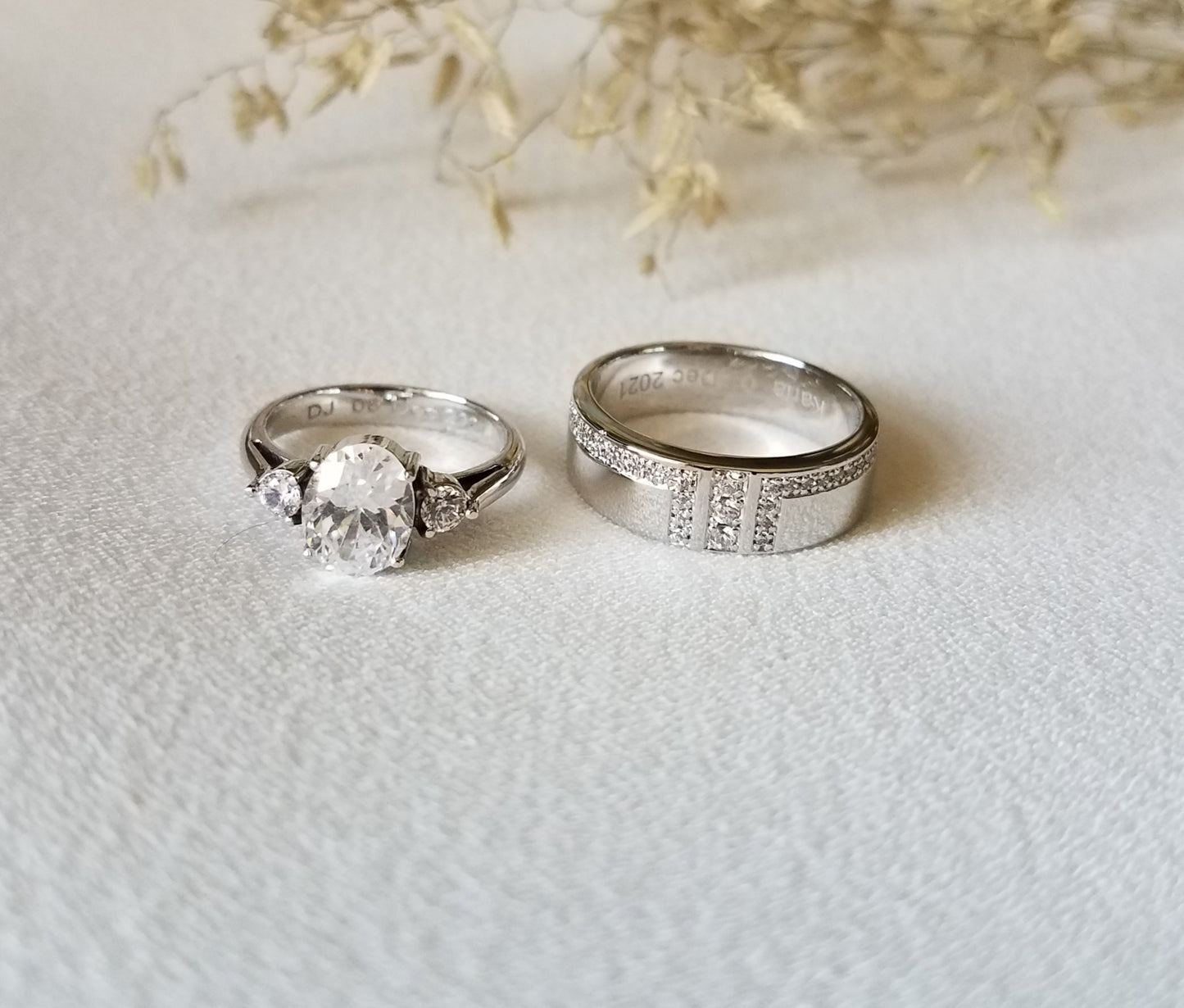 White gold wedding rings. Groom with approximately 30 white sapphires all around the ring itself. Bride: with an oval whute sapphire as the center stone ans 2 small round sapphires at the side.