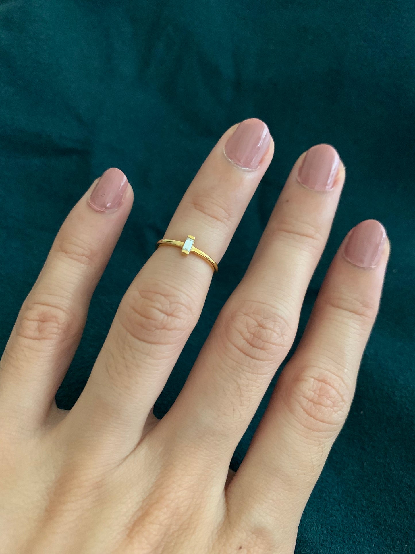 An emerald signity cut on a vertical way, also on a thin yellow gold ring.