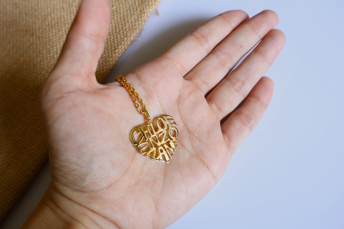 Handmade 14K gold custom heart name necklace with a personalized name cutout pendant, measuring 2.5cm x 2.5cm, displayed on a white surface.
