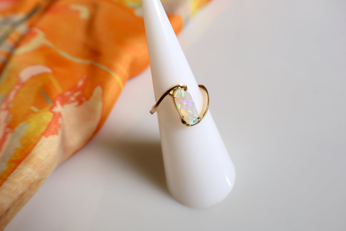 Handmade 14K gold opal ring featuring a luminous oval opal gemstone in a modern flowing gold setting, custom crafted