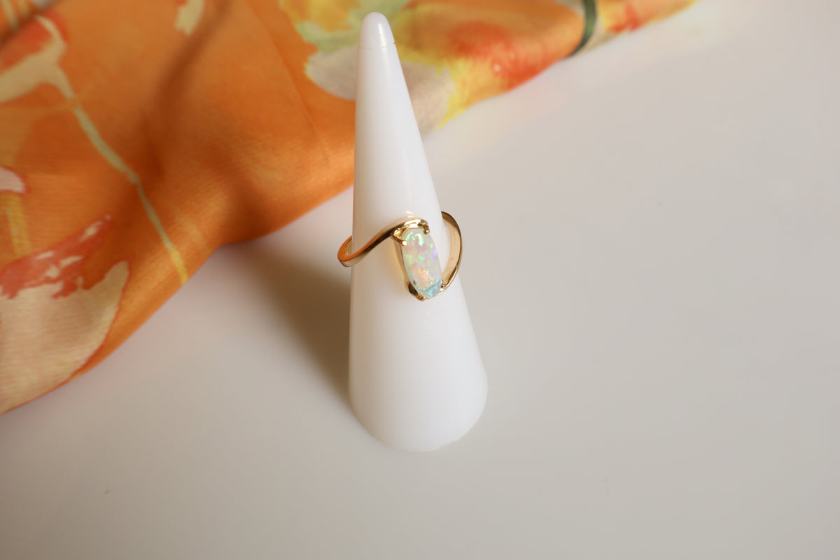 Handmade 14K gold opal ring featuring a luminous oval opal gemstone in a modern flowing gold setting, custom crafted