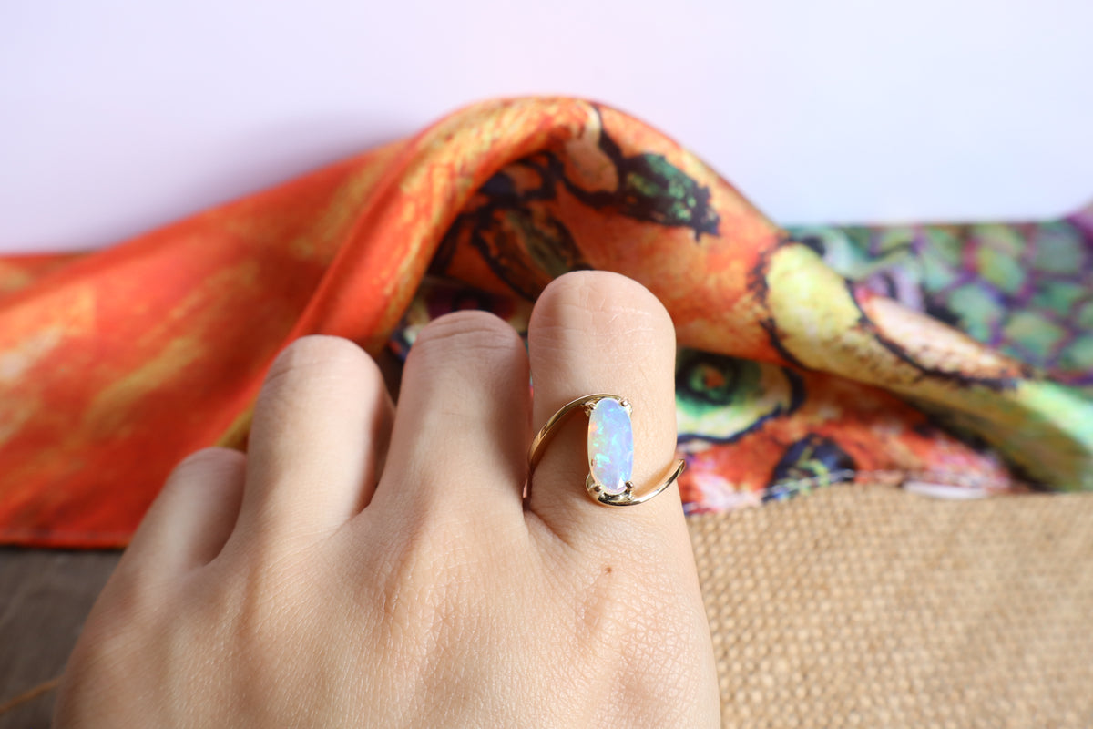 Handmade 14K gold opal ring featuring a luminous oval opal gemstone in a modern flowing gold setting, custom crafted