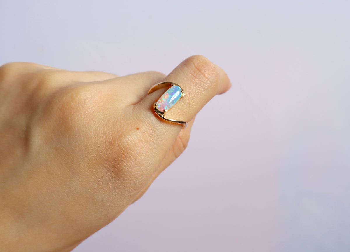 Handmade 14K gold opal ring featuring a luminous oval opal gemstone in a modern flowing gold setting, custom crafted