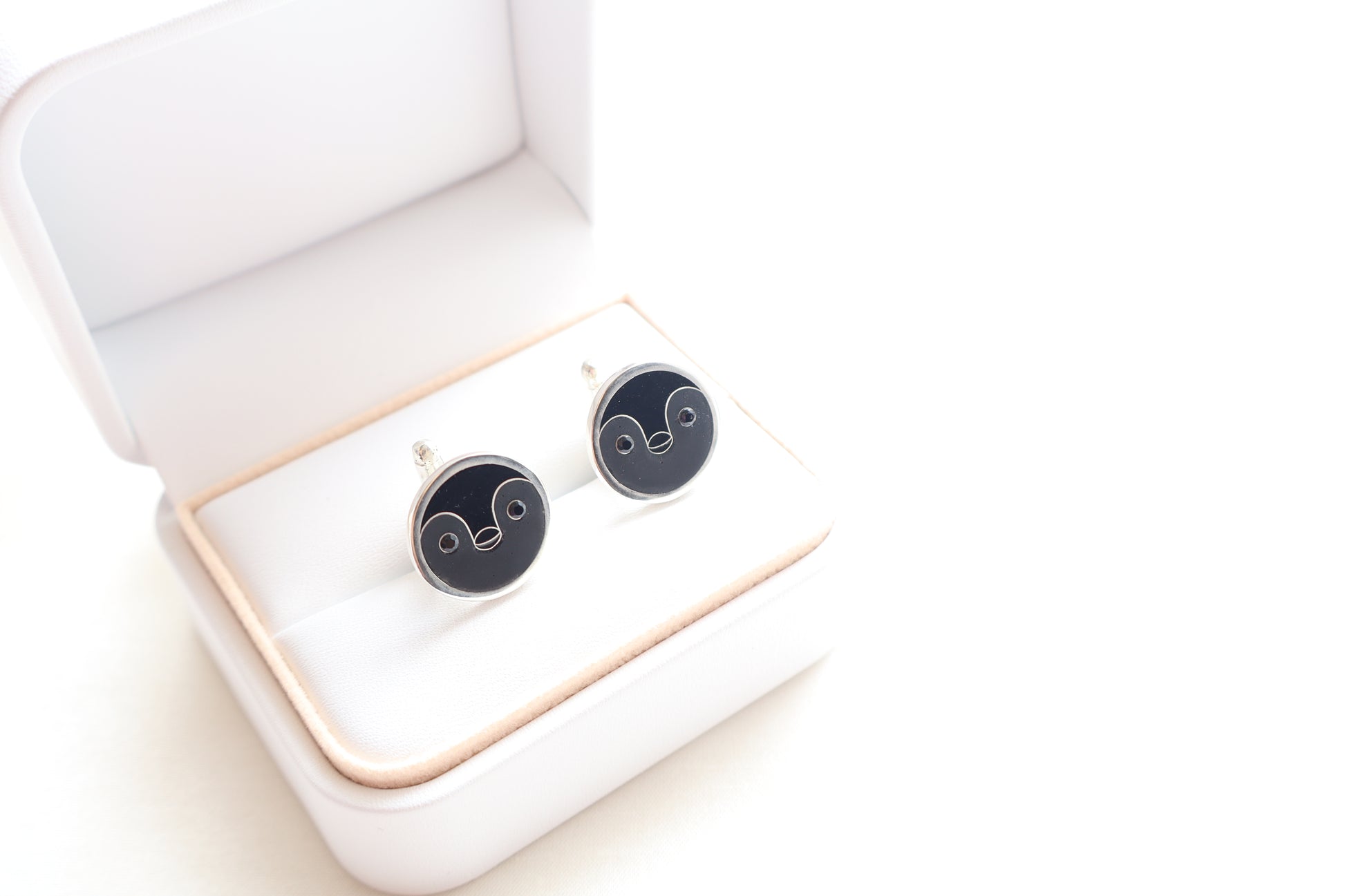 Custom 925 silver cufflinks with matte and glossy enamel and black onyx eyes, designed as a penguin face. A modern jewelry gift in Singapore with refined packaging.