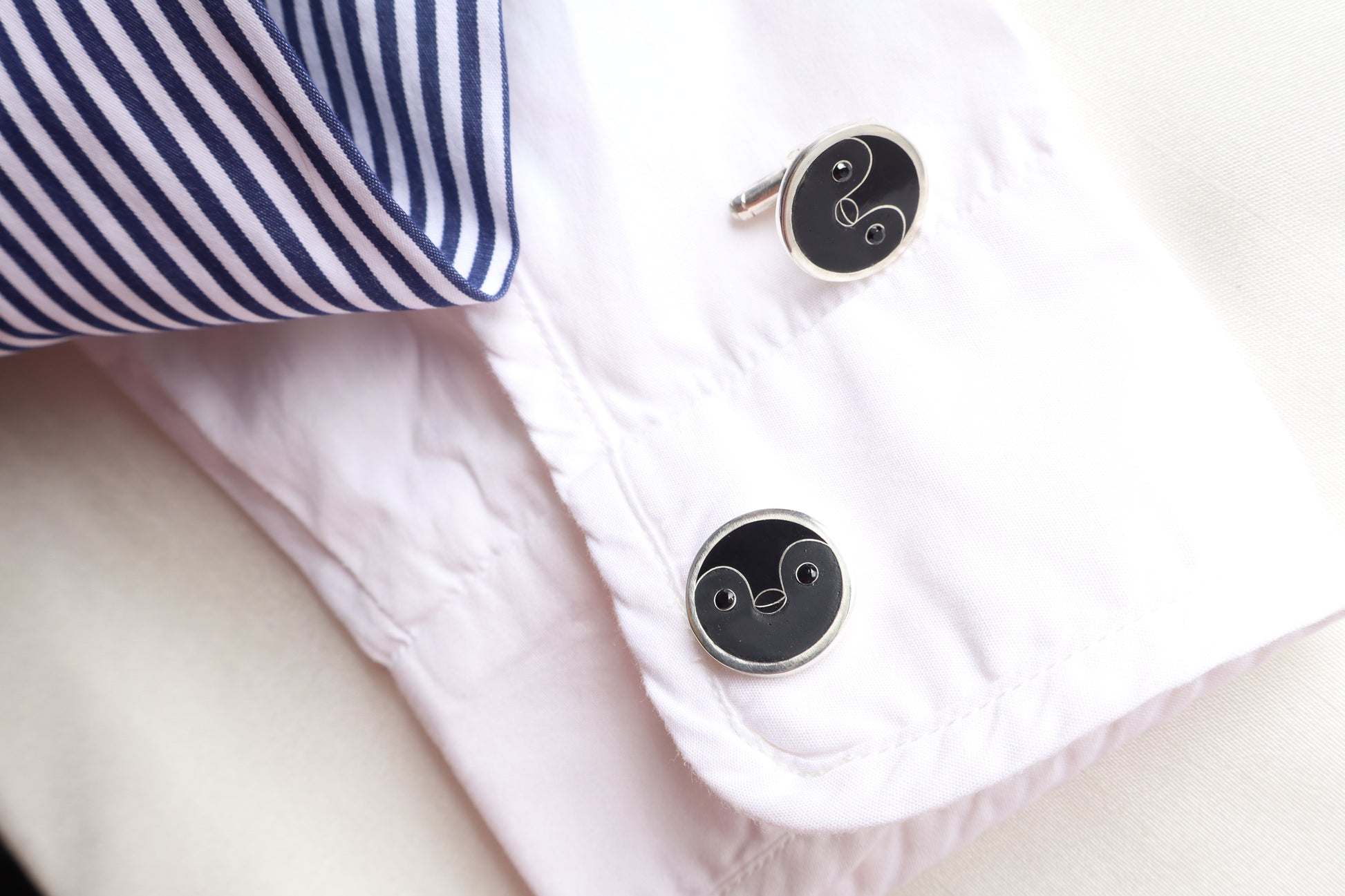 Custom 925 silver cufflinks with matte and glossy enamel and black onyx eyes, designed as a penguin face. A modern jewelry gift in Singapore with refined packaging.