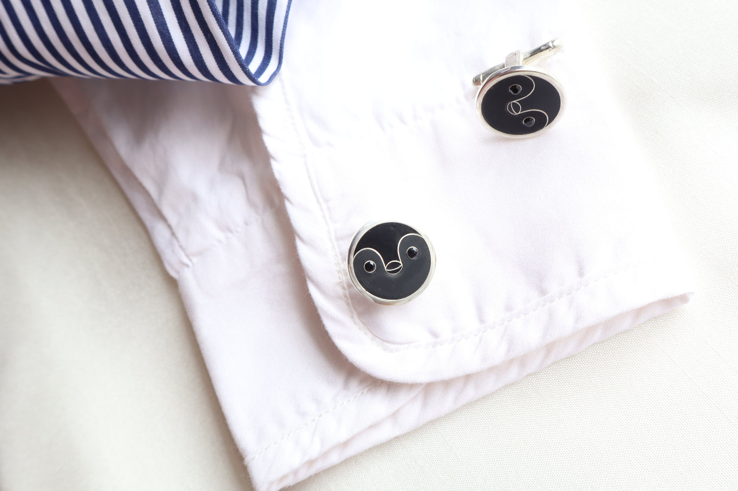 Custom 925 silver cufflinks with matte and glossy enamel and black onyx eyes, designed as a penguin face. A modern jewelry gift in Singapore with refined packaging.