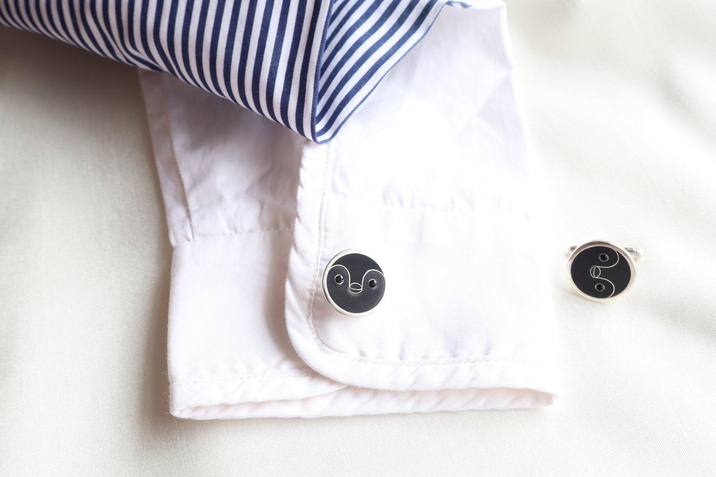Custom 925 silver cufflinks with matte and glossy enamel and black onyx eyes, designed as a penguin face. A modern jewelry gift in Singapore with refined packaging.