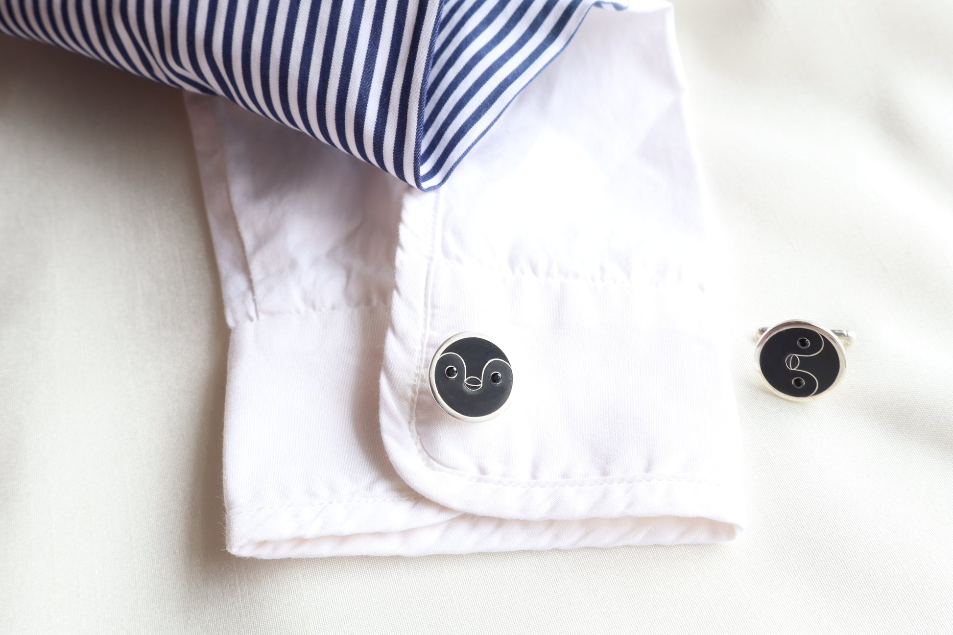 Custom 925 silver cufflinks with matte and glossy enamel and black onyx eyes, designed as a penguin face. A modern jewelry gift in Singapore with refined packaging.