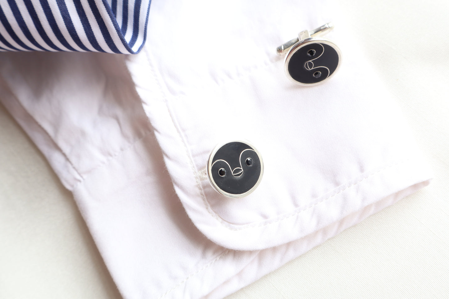 Custom 925 silver cufflinks with matte and glossy enamel and black onyx eyes, designed as a penguin face. A modern jewelry gift in Singapore with refined packaging.