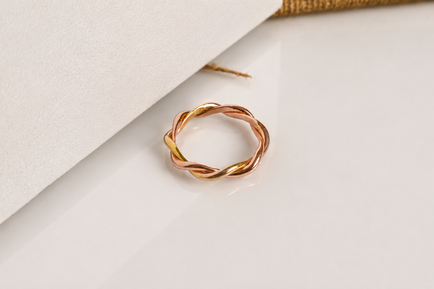 Handcrafted 18K two-tone yellow gold and rose gold twisted ring with an elegant intertwined design. Bespoke jewelry by a Singapore jewelry supplier, ideal for premium corporate gifts and abaca packaging presentations.