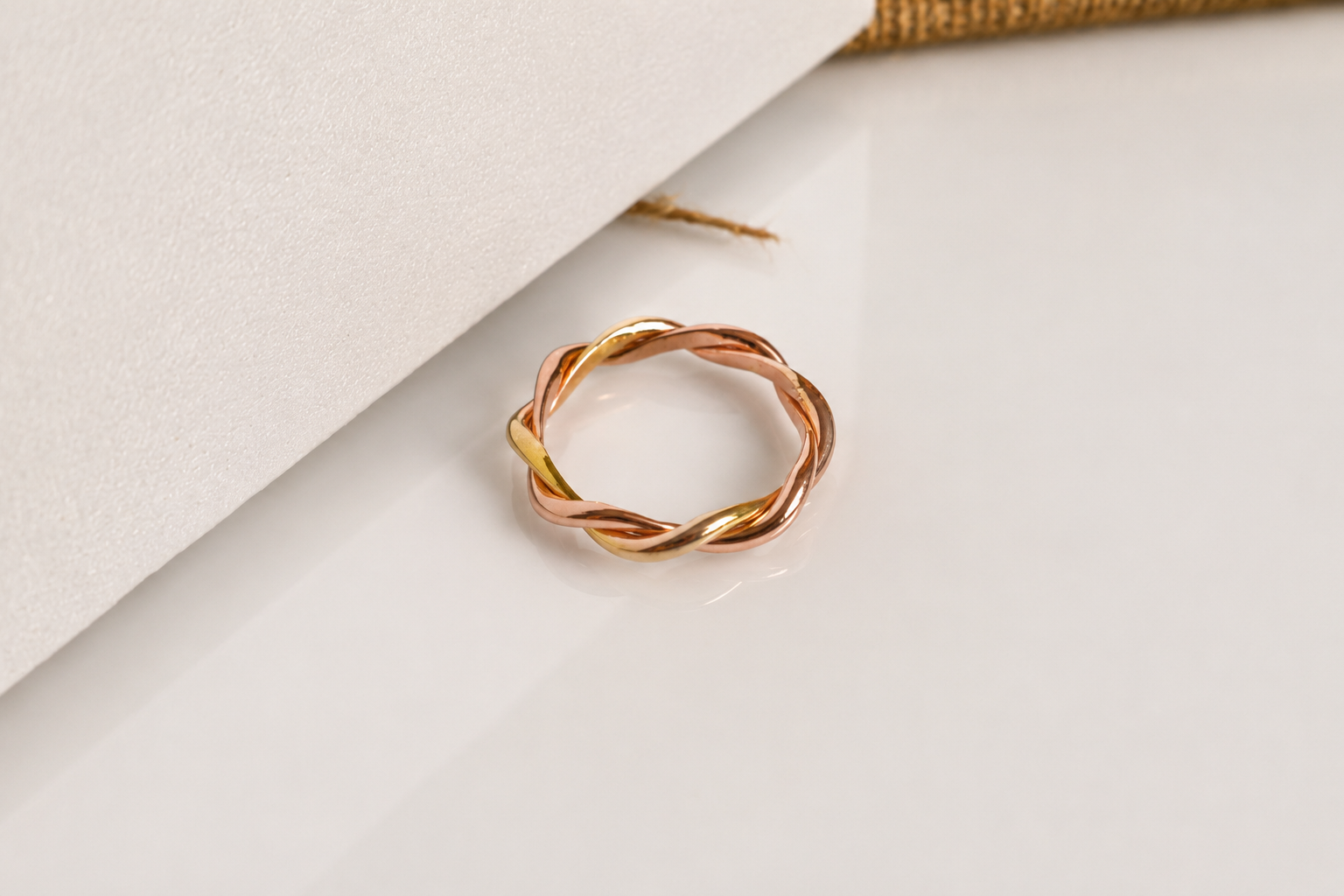 Handcrafted 18K two-tone yellow gold and rose gold twisted ring with an elegant intertwined design. Bespoke jewelry by a Singapore jewelry supplier, ideal for premium corporate gifts and abaca packaging presentations.