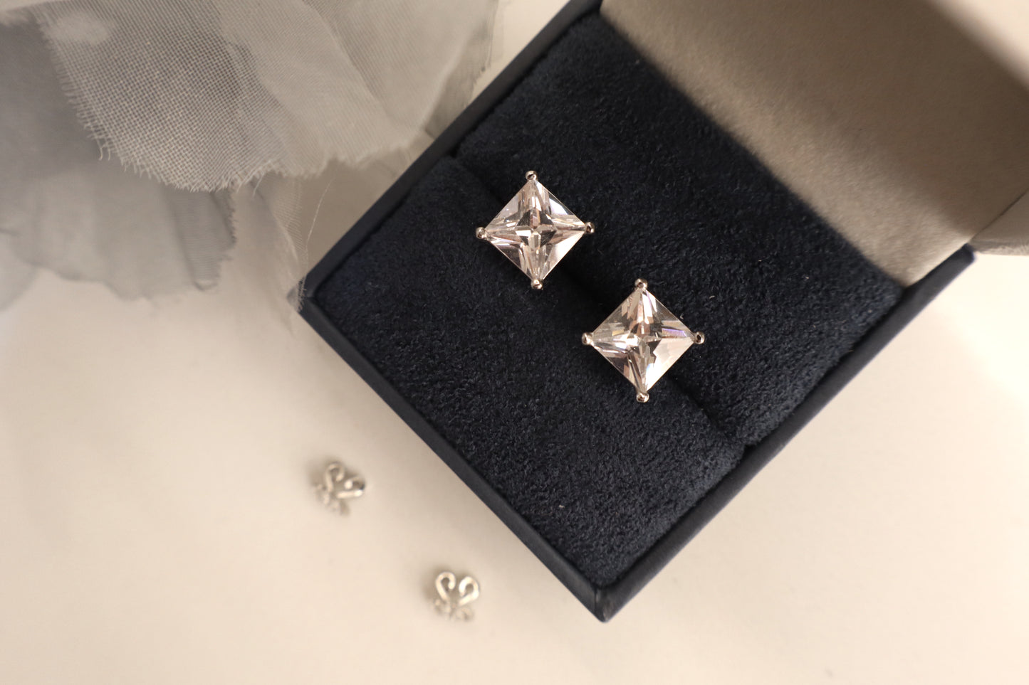 14K white gold stud earrings featuring 7mm princess cut Signity stones set in a sleek modern design, radiating brilliance. Sustainable jewelry packaging for Singapore corporate awards and bespoke fine jewelry.