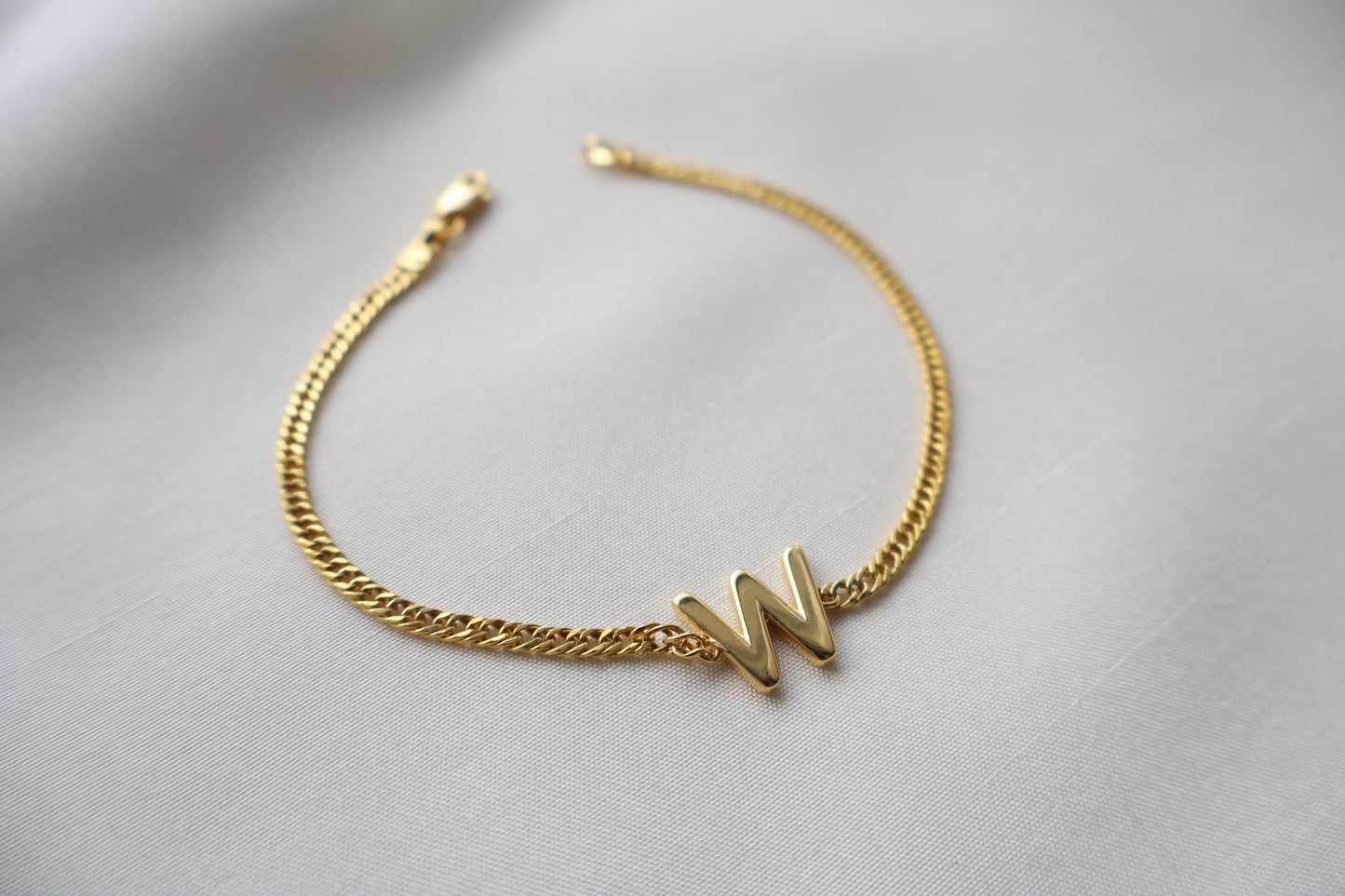 14K yellow gold bracelet with a polished reversible letter charm shaped as M or W on a fine chain, personalized sentimental gift jewelry.
