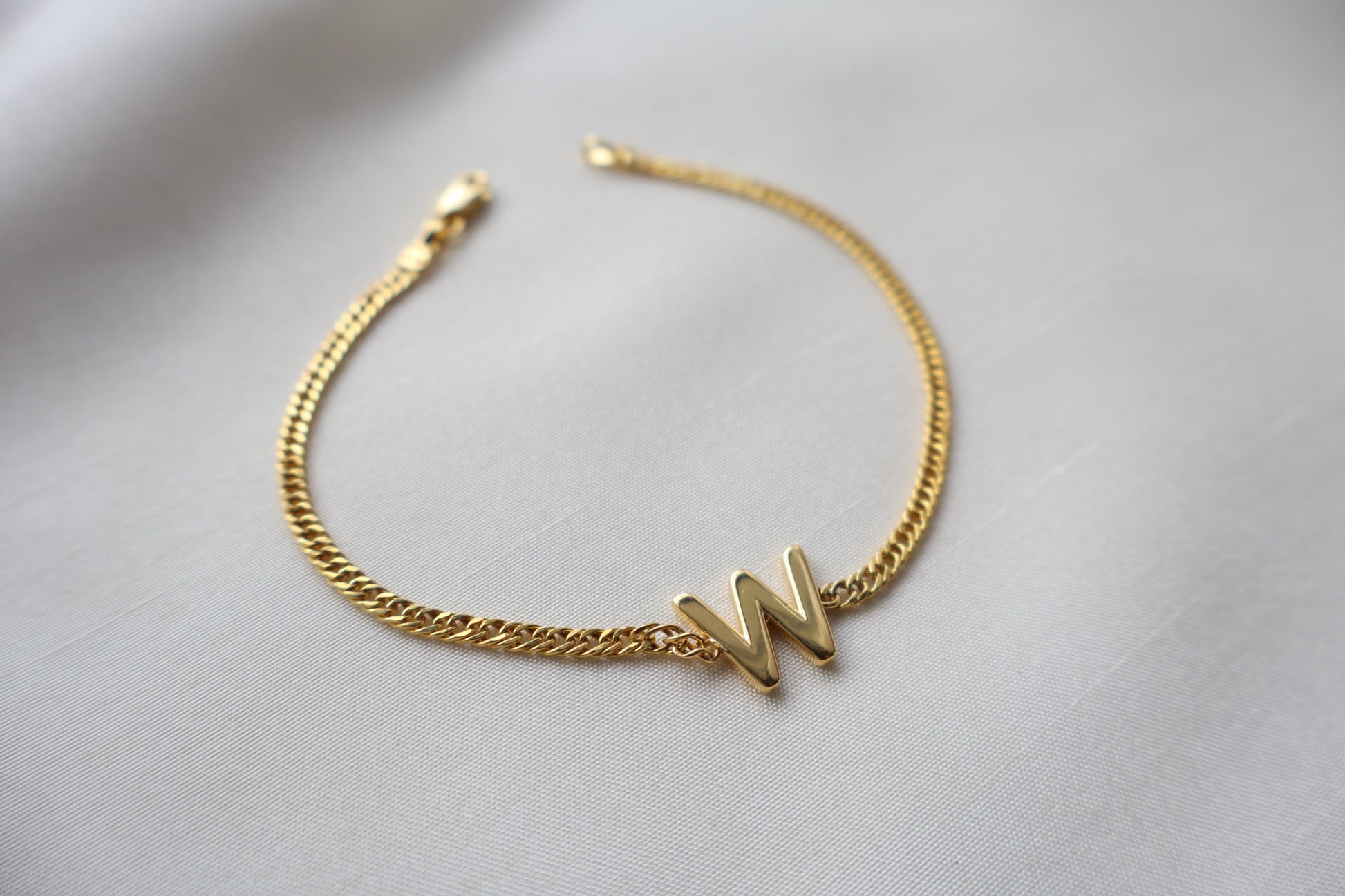 14K yellow gold bracelet with a polished reversible letter charm shaped as M or W on a fine chain, personalized sentimental gift jewelry.