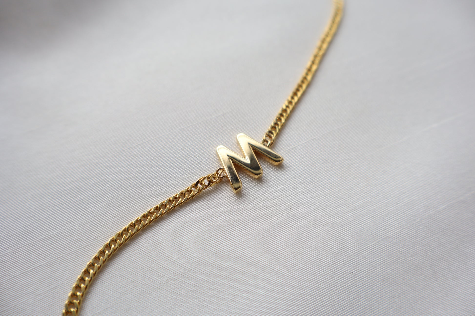 14K yellow gold bracelet with a polished reversible letter charm shaped as M or W on a fine chain, personalized sentimental gift jewelry.