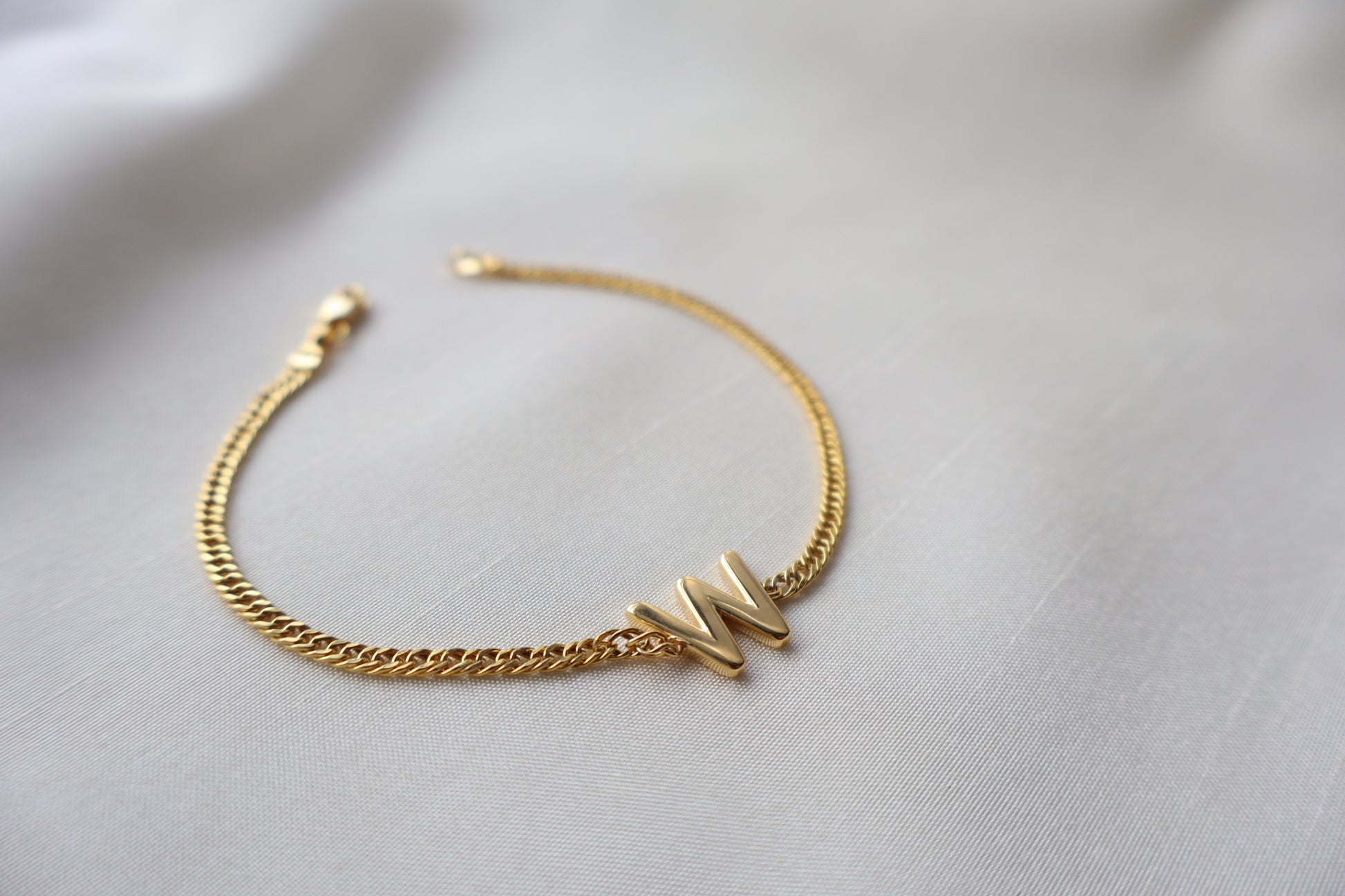 14K yellow gold bracelet with a polished reversible letter charm shaped as M or W on a fine chain, personalized sentimental gift jewelry.