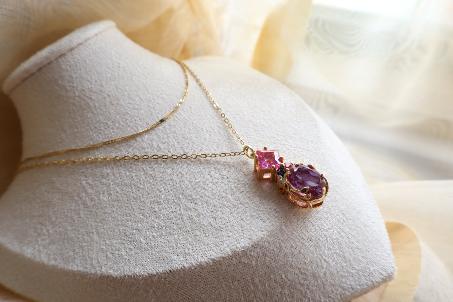 Custom necklace with an oval-cut alexandrite pendant accented by rubellite, ruby, blue sapphire, and natural diamonds on layered chains. Eco-friendly corporate gift jewelry in abaca packaging, bespoke design for Singapore companies.