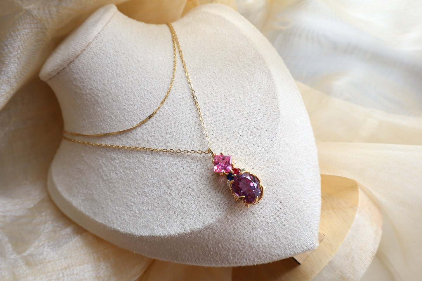 Custom necklace with an oval-cut alexandrite pendant accented by rubellite, ruby, blue sapphire, and natural diamonds on layered chains. Eco-friendly corporate gift jewelry in abaca packaging, bespoke design for Singapore companies.