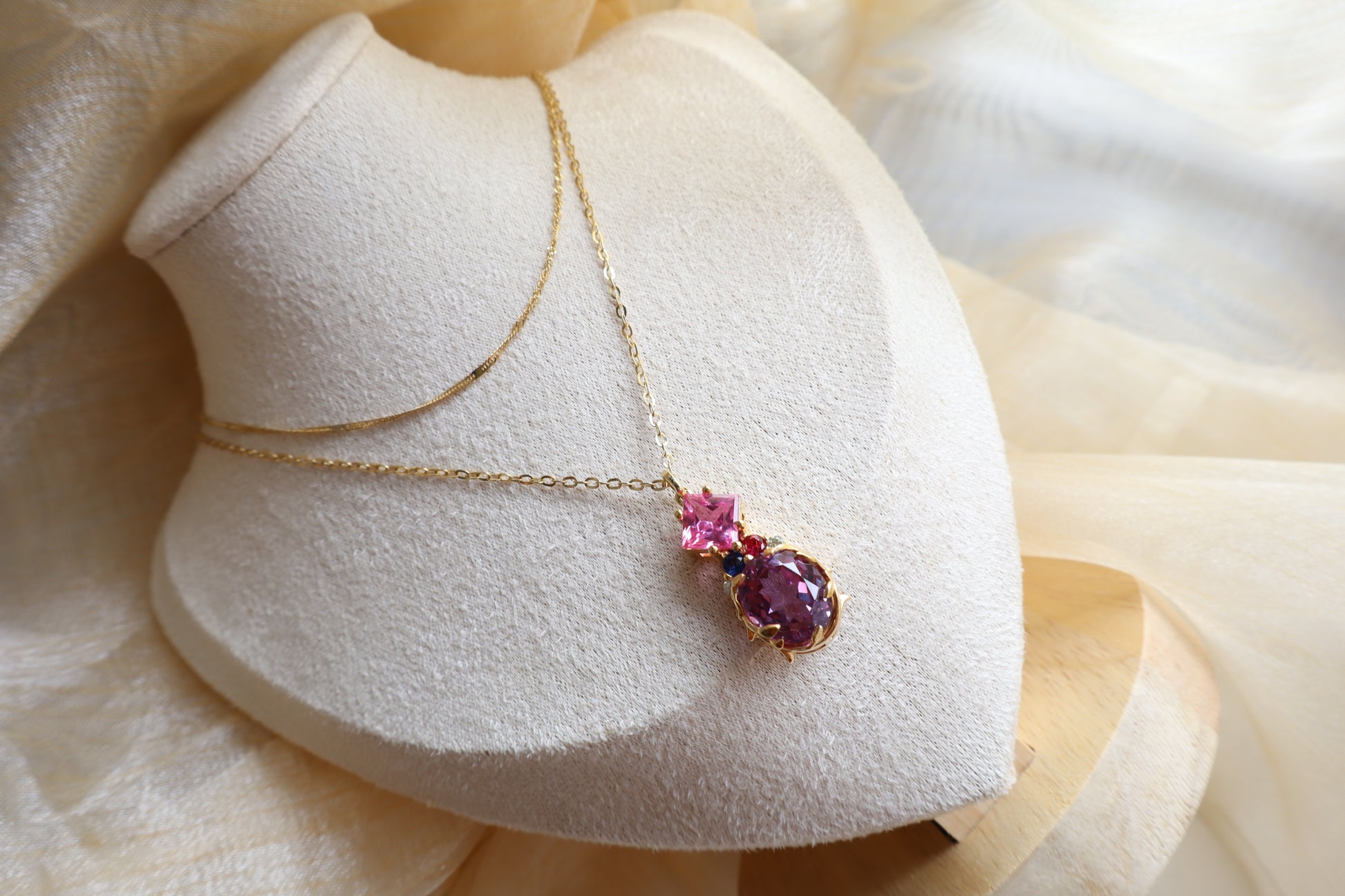 Custom necklace with an oval-cut alexandrite pendant accented by rubellite, ruby, blue sapphire, and natural diamonds on layered chains. Eco-friendly corporate gift jewelry in abaca packaging, bespoke design for Singapore companies.