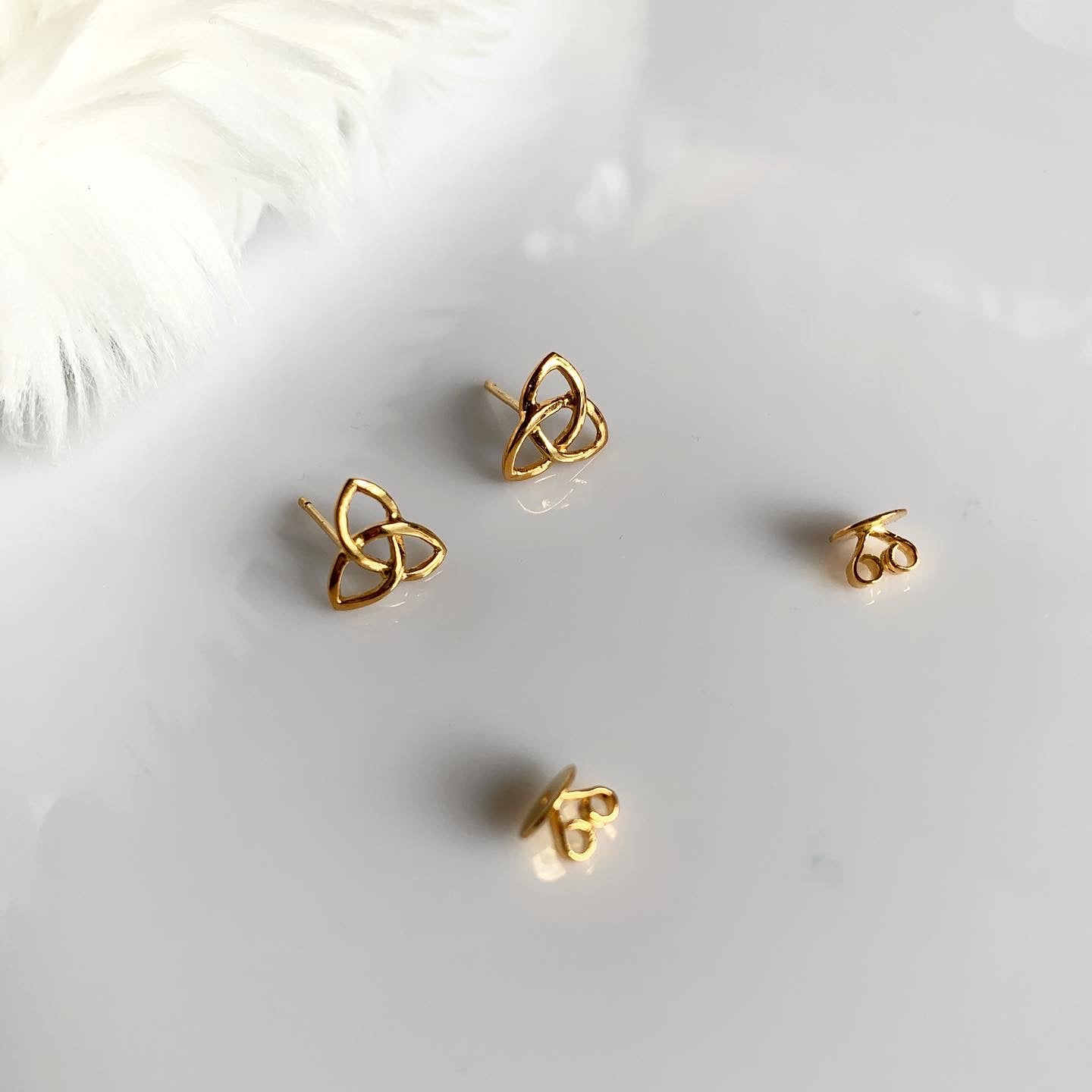 A gold pair of triquetra stud earrings.