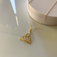 Load image into Gallery viewer, A gold triquetra pendant serves as a ring holder.
