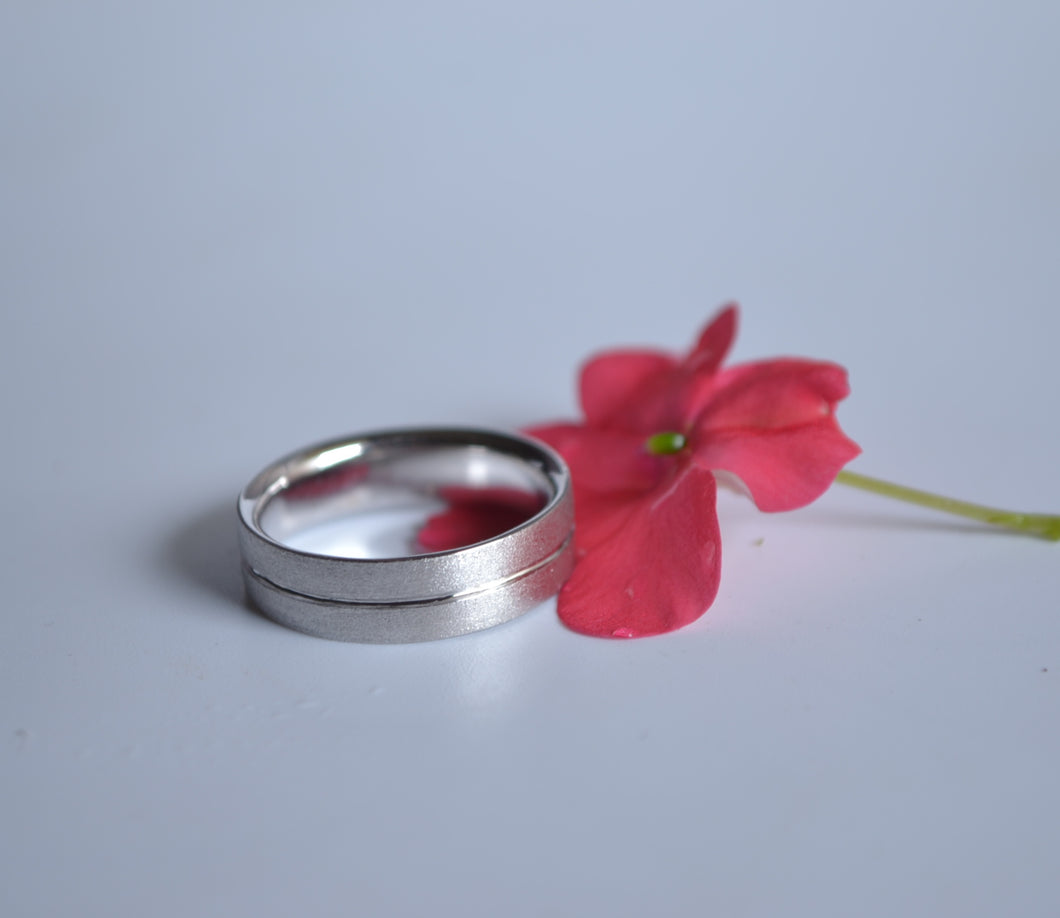 A silver wedding ring with a silver lining at the center.