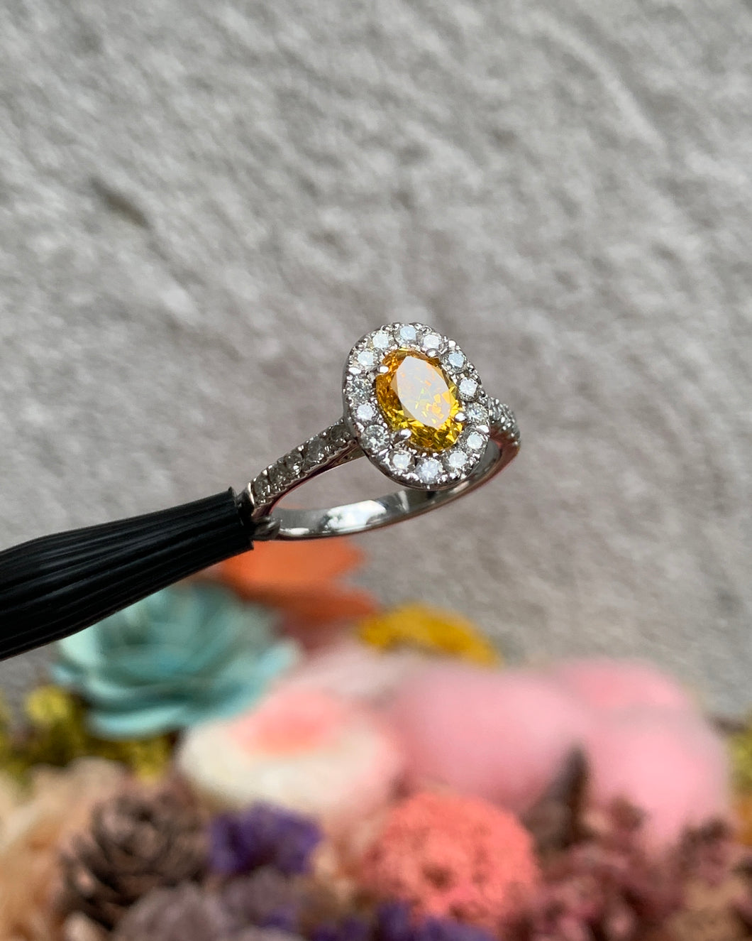 An oval bright yellow sapphire with a halo of small round diamonds. Also, with 5 round diamonds on each shoulders. Set in 14k white gold.
