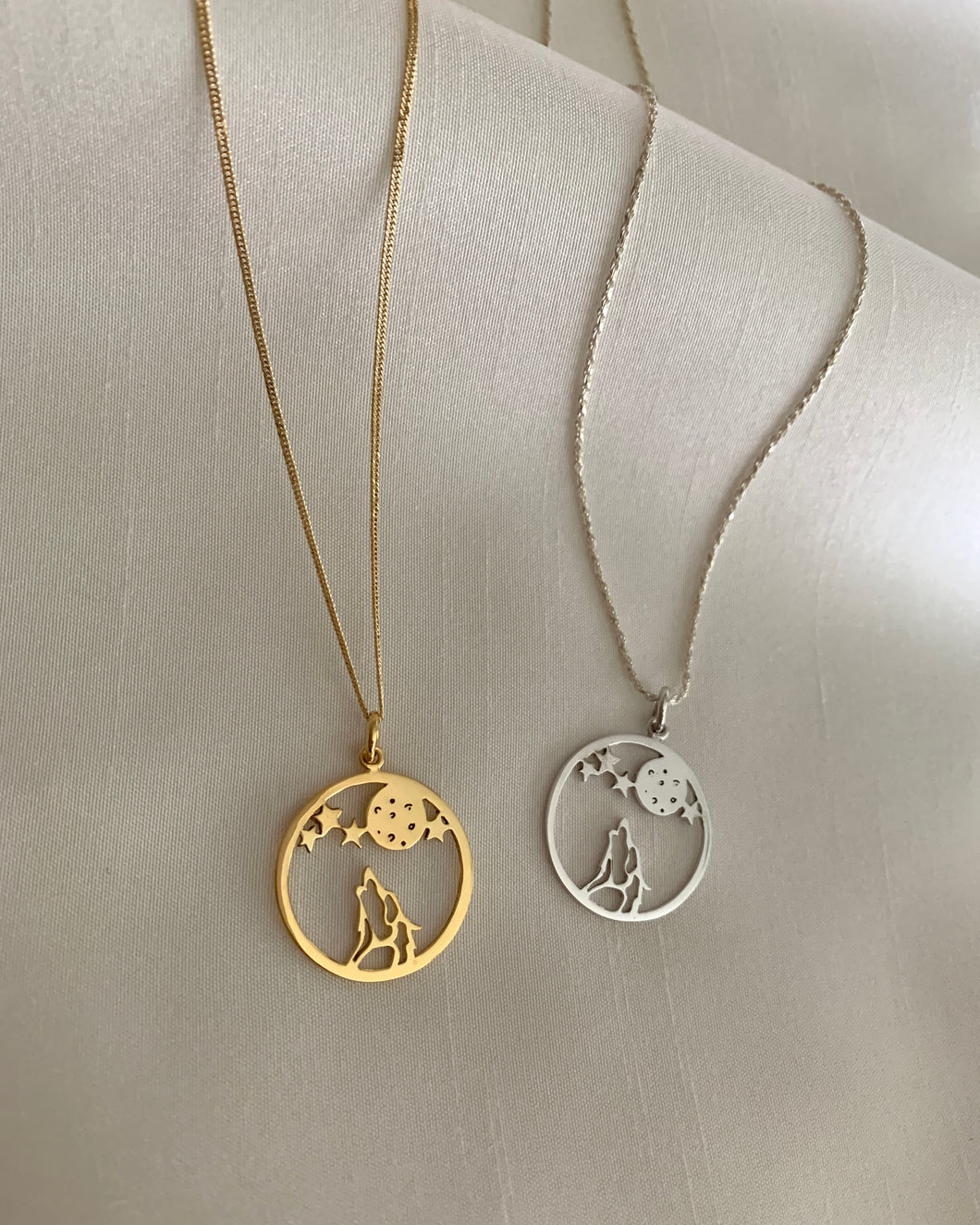 A howling wolf underneath the moon and stars. Set in yellow gold and white gold.
