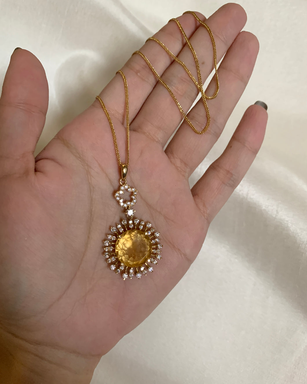 A round yellow citrine stone in bezzle moissanites and set in yellow gold. 