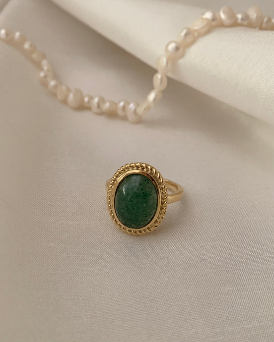 An oblong jade stone put into a yellow gold ring. 