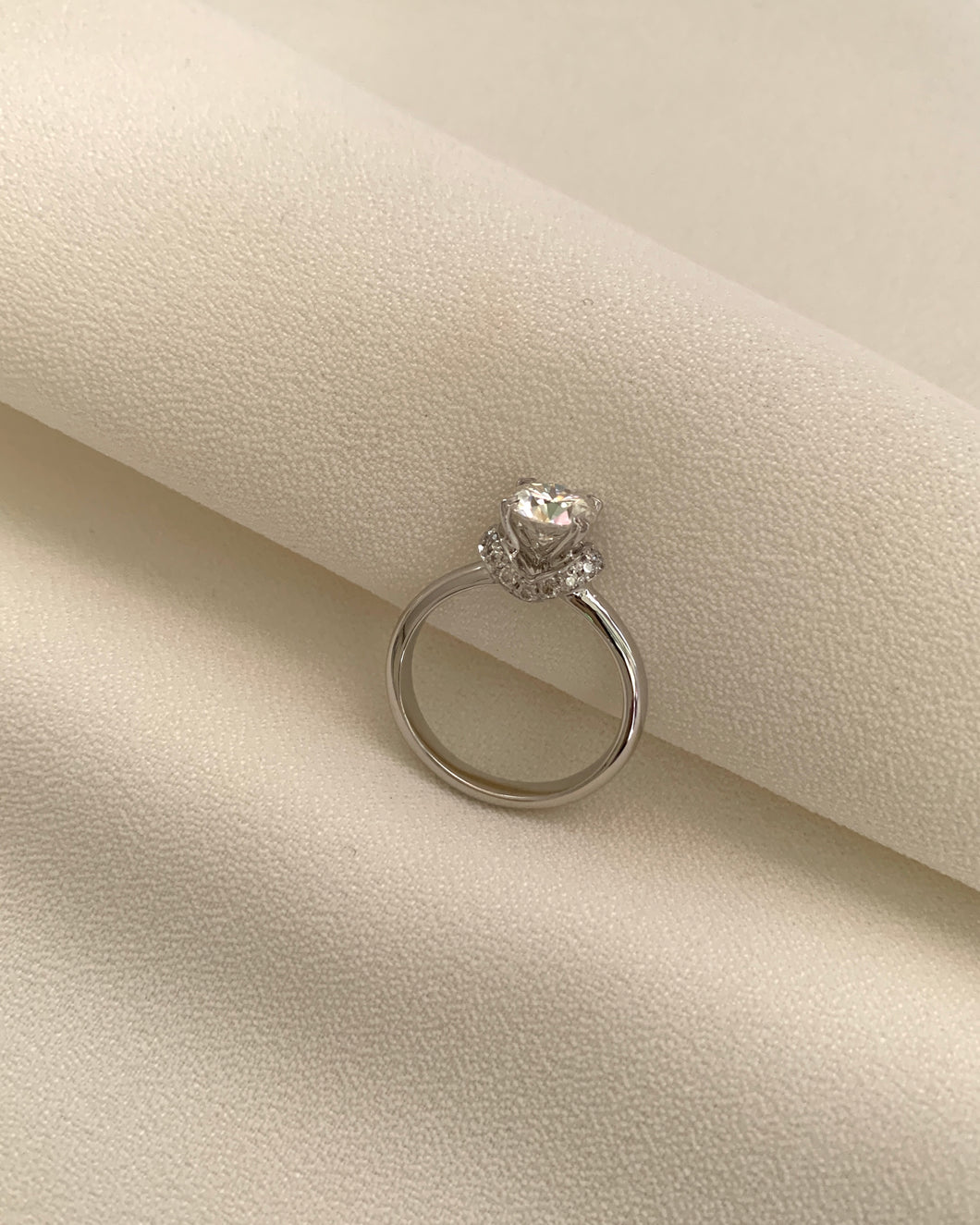 A 1 Carat Round Moissanite with An Enclustered Diamond Collar Set in 14K White Gold.