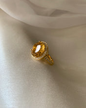 Load image into Gallery viewer, An oval protruded citrine ring in a halo style put together in a moissanites band. Set in yellow gold.

