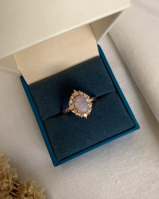 An opal oval gemstone with 10 pieces of small round diamonds set in a floral design. All in a 14k rose gold band.