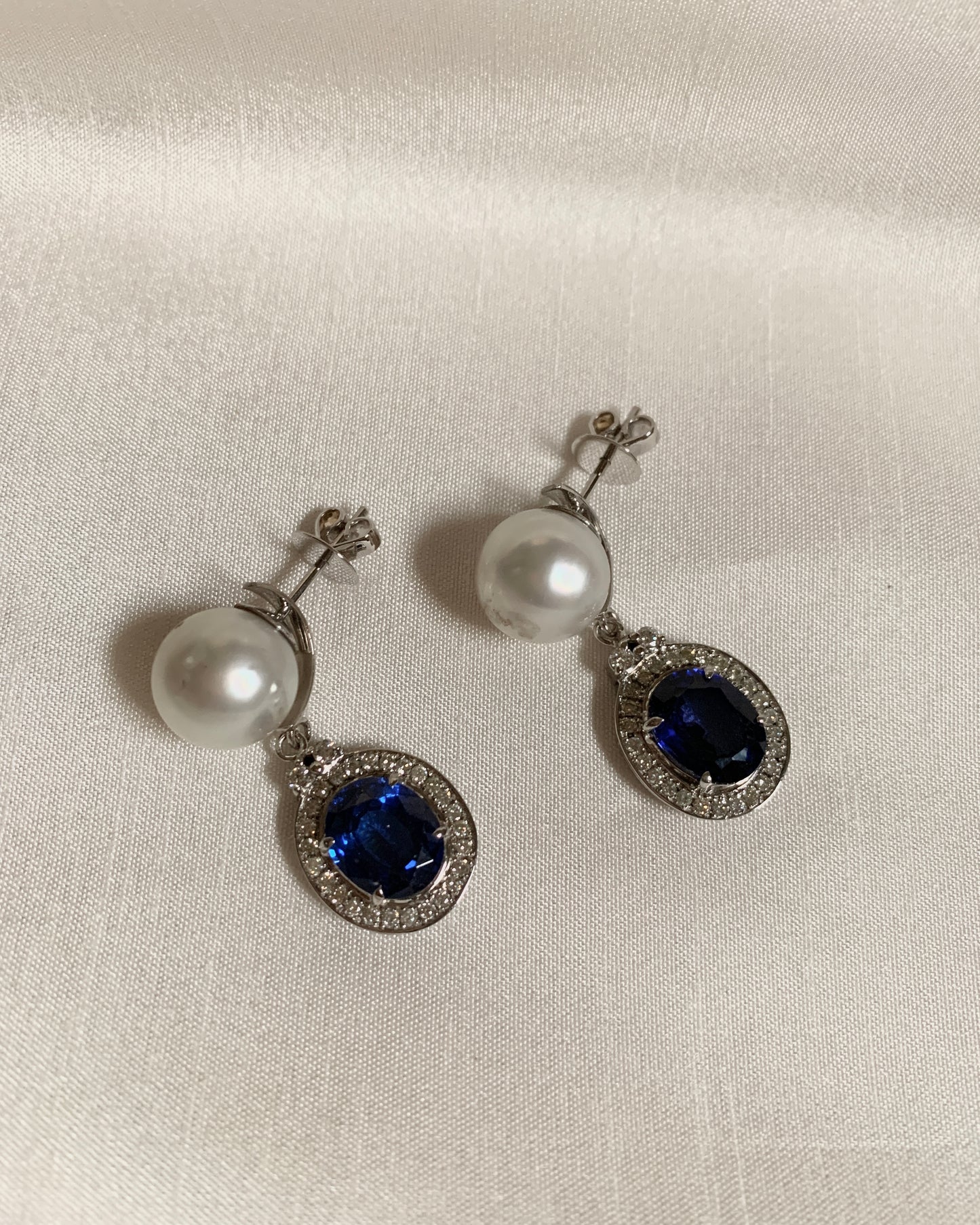 A pair oval blue sapphire with a south sea pearl above it. Blue sapphires were crowned with small diamonds. 