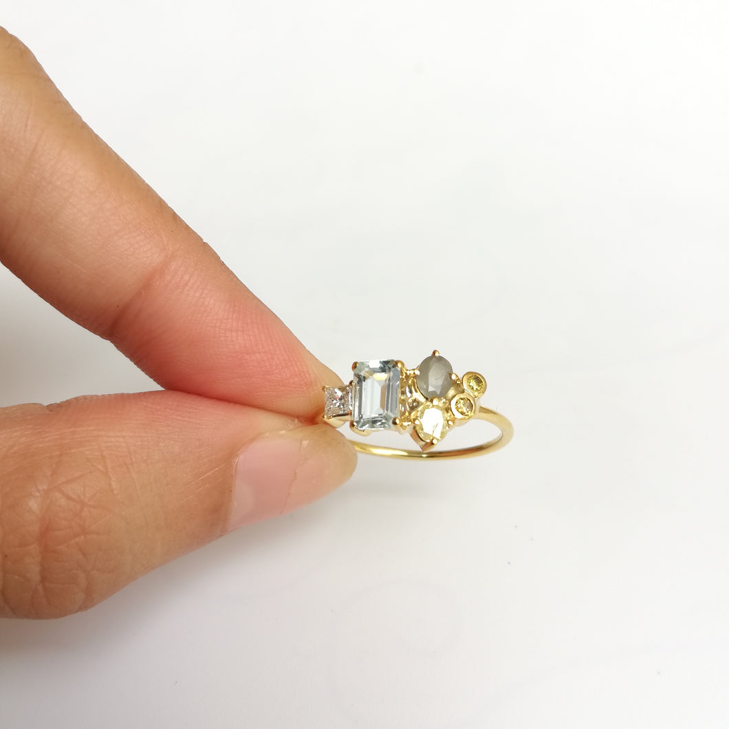 A dainty ring with 2 small diamonds at the right center then 3 differemt gemstones for the center and the left side. All set in yellow gold.