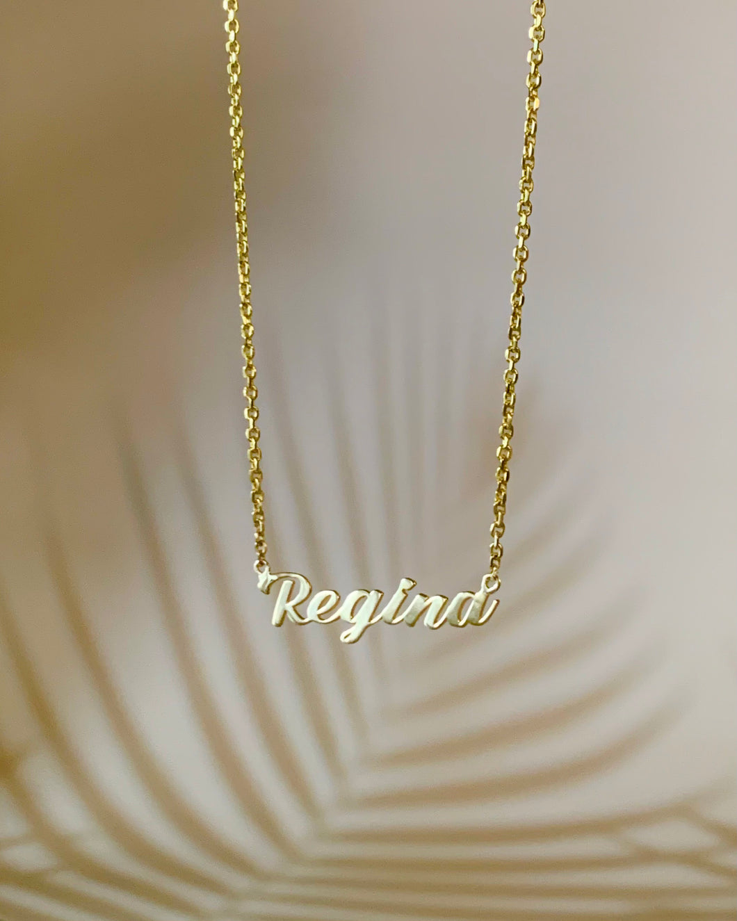 Customized gold Regina name necklace.