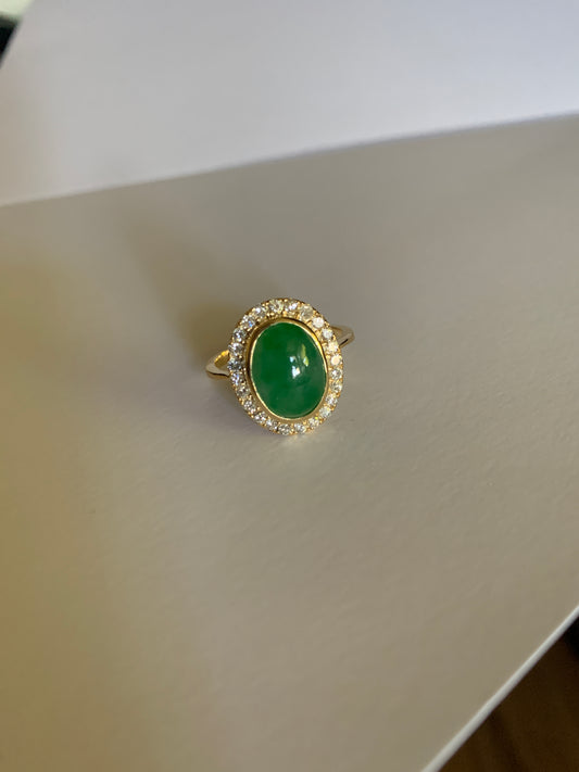 An oval jade stone with diamomd bezzles set in yellow gold.